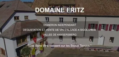 Vue extérieure du Domaine Fritz, vigneron indépendant situé à Sigolsheim, au cœur de la vallée de Kaysersberg en Alsace. Bâtisse typiquement alsacienne à colombages, façade claire et volets rouges, symbole du savoir-faire viticole transmis depuis plusieurs générations. Le Domaine Fritz incarne l’excellence des vins d’Alsace élaborés avec passion et respect du terroir : Riesling, Pinot Gris, Gewurztraminer, Crémant et autres grands crus issus des coteaux ensoleillés. L’ambiance du lieu traduit la tradition, la convivialité et la fierté d’un artisan vigneron attaché à sa terre. Cette image met en avant la qualité, l’authenticité et la proximité du producteur. Site internet conçu et optimisé par ABC WEB, agence web spécialisée en création de sites professionnels pour vignerons, domaines viticoles et producteurs locaux en France 🇫🇷. ABC WEB 🌐 valorise les savoir-faire régionaux à travers des visuels immersifs, des contenus SEO performants et une architecture web pensée pour la visibilité sur Google, tout en respectant l’identité du terroir alsacien et la singularité du Domaine Fritz.